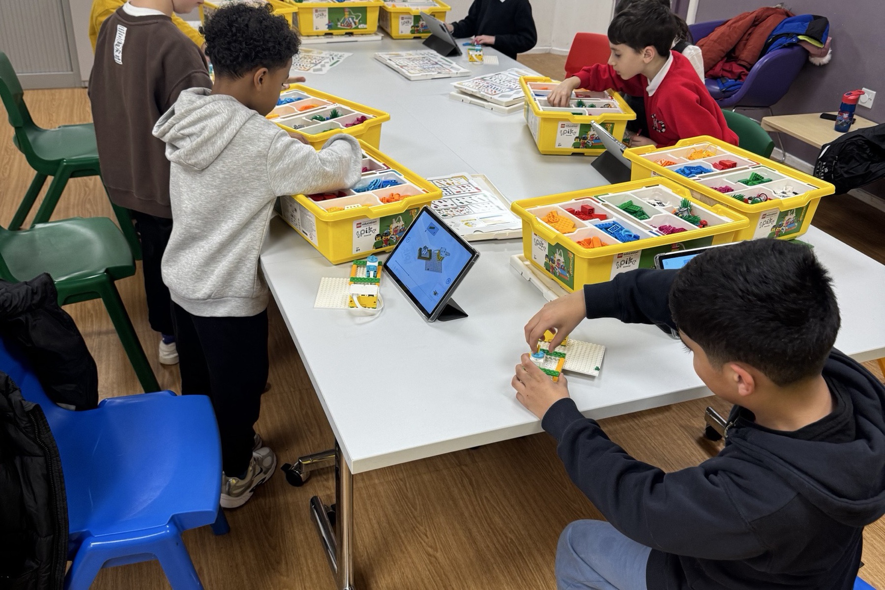 Children working together with LEGO building kits and tablets around a table.